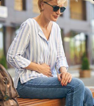 woman on outdoor bench having stomachache