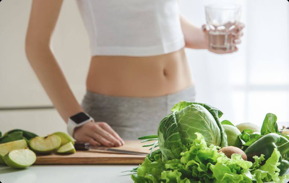 Woman behind kitchencounter full of greens