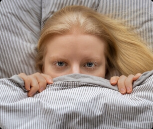 Vrouw ligt onder de dekens op bed